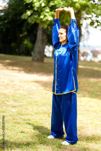 Fotografie Woman practicing tai chi qigong in a blue uniform