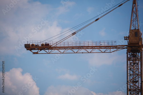 Close-up of a yellow tower crane jib end against clear blue sky with large copy space