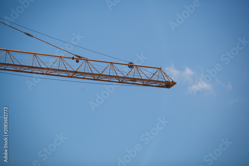 Fotografie Close-up of a yellow tower crane jib end against clear blue sky with large copy
