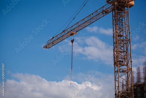 Schilderij op canvas Close-up of a yellow tower crane jib end against clear blue sky with large copy