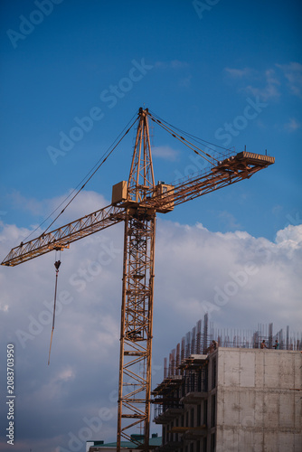 Tableau sur toile Close-up of a yellow tower crane jib end against clear blue sky with large copy