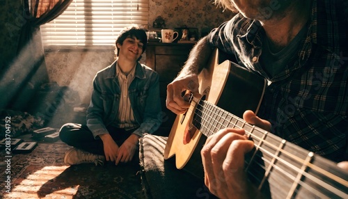 He loves listening to his dad play. Shot of a young man listening to his father play the guitar at home.