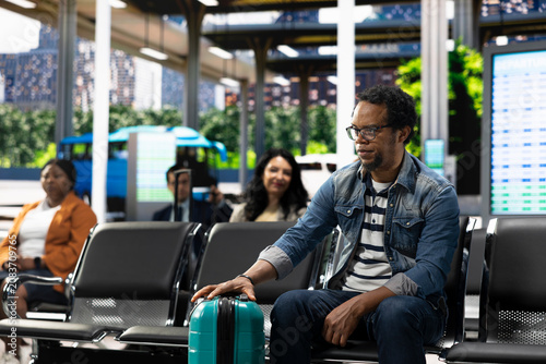 Fényképezés Solo traveler in crowded bus terminal, preparing for long-distance interstate journey, traveler with carry-on luggage ready for affordable express coach at bus stop, for commuter transport concepts