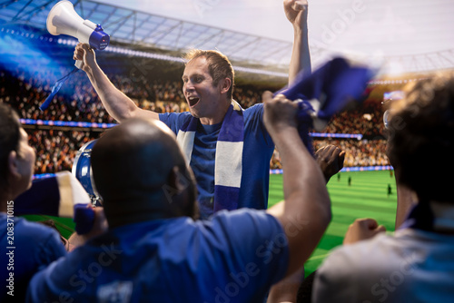 Foto Football supporters raise arms and chant from stadium stands during match day, cheering crowd, scarf