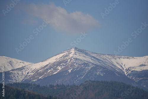Majestic snowy mountain peak with triangular pyramid shape against clear blue sky in winter.