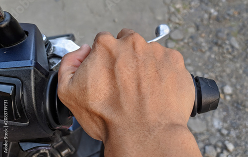 Close-up of motorcyclist hands gripping handlebars, riding motorbike on road. POV shot of hands steering a motorcycle