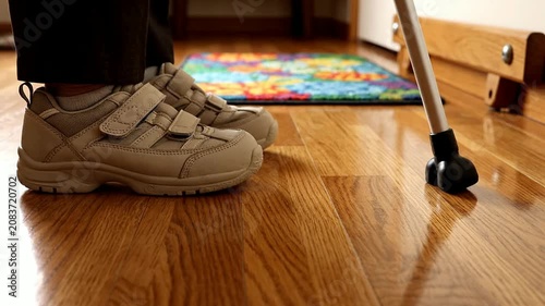 Low-Angle Static Shot Of Senior's Feet In Supportive Orthopedic Shoes On Hardwood Floor Near Colorful Mat