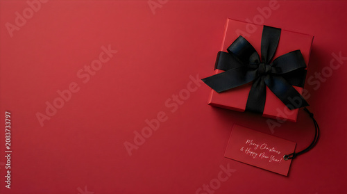 Christmas gift box with black ribbon and tag on red background