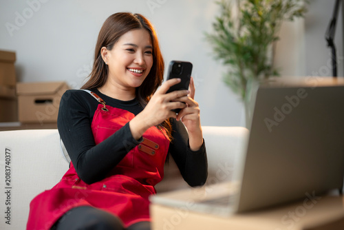 Foto Happy Woman in Red Apron Using Smartphone While Sitting on Couch