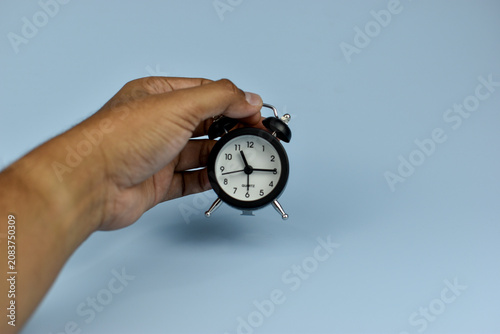 Cuadro en lienzo Hand holds vintage alarm clock against soft blue background