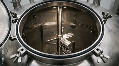 Pharmaceutical mixing tank's agitator shaft visible through an open manway hatch - Pharmaceutical Manufacturing Stock Photo