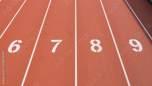 Running track lanes with white lines and numbers six seven eight nine on red surface