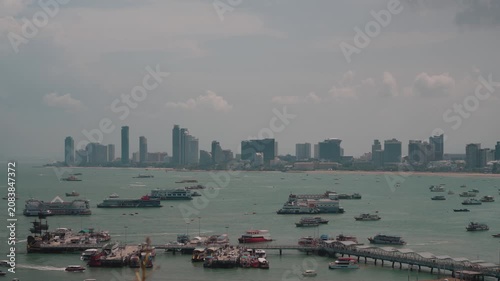 panoramic Pattaya Bay in Thailand featuring numerous anchored boats, turquoise sea, and the modern city skyline in the background during daytime. Ideal for travel, tourism, coastal city