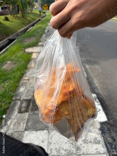 Foto Close-up of popular Indonesian street food, crispy deep-fried snacks inside a clear plastic bag being held by hand
