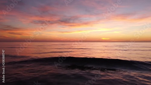 Vibrant sunset over calm ocean waves on the horizon.