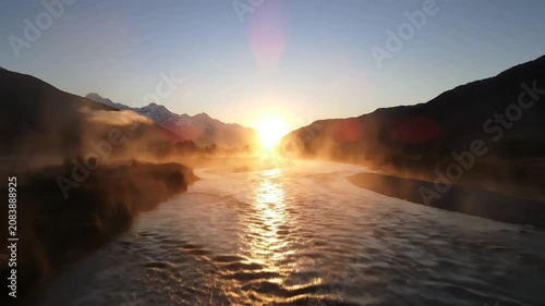 Misty river flowing between mountains at golden hour sunrise.