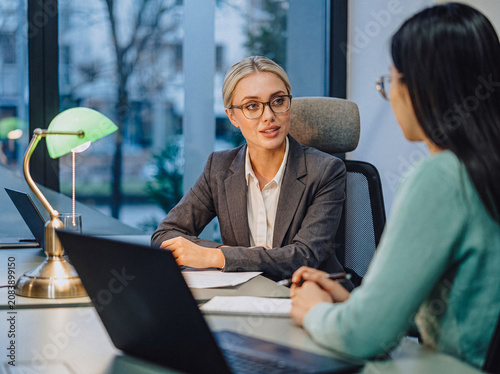 Photos Professional photograph of two diverse businesswomen engaged in a focused one-on-one meeting or interview in an office