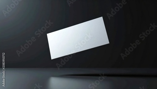 Blank white business card floating in minimalist dark studio, perfect for mockup and design template
