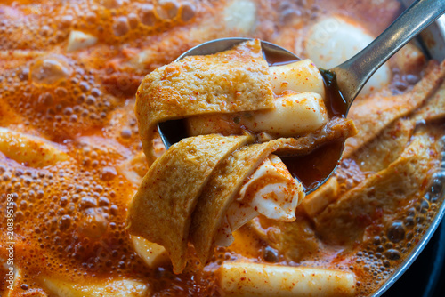 Sliced fish cake and rice cake scooped with a metal ladle from Tteokbokki pot