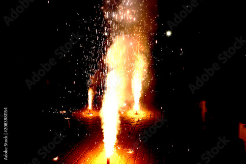 Ground Firework Fountains – Bright Yellow Orange Sparks with Glowing Flames on Brick Surface Against Dark Festive Night Concept