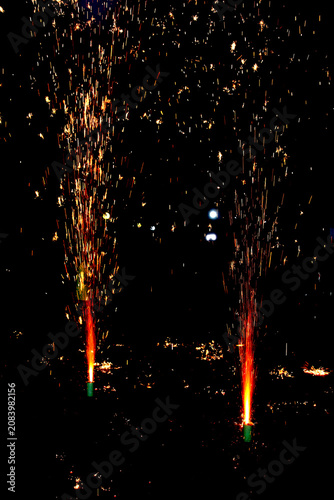 Ground Firework Fountains – Twin Tall Orange Yellow Sparks with Glowing Trails and Illuminated Motion Against Dark Festive Night Concept
