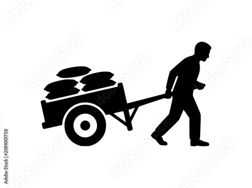 Silhouette of a man pulling a heavy handcart loaded with sacks