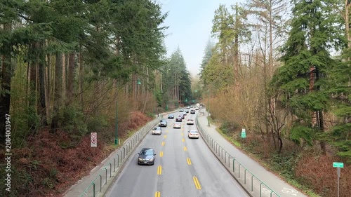 Traffic on tree-lined causeway road through forest in Stanley Park, Vancouver