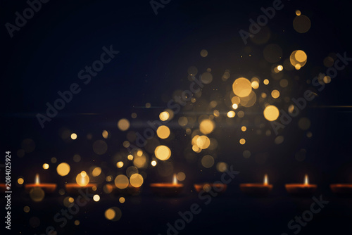 Golden bokeh lights over burning candles, festive glowing background with warm sparkles, magical holiday atmosphere with soft light circles