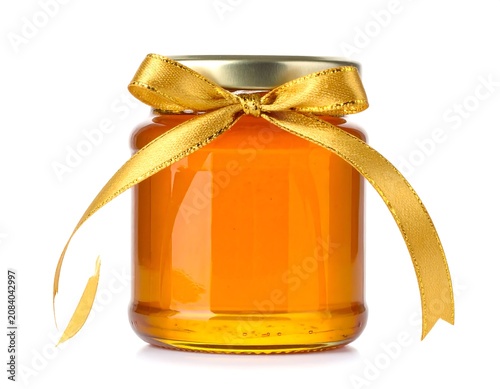 A jar filled with golden liquid, sealed with a metal lid and adorned with a tied golden ribbon bow. The background is white