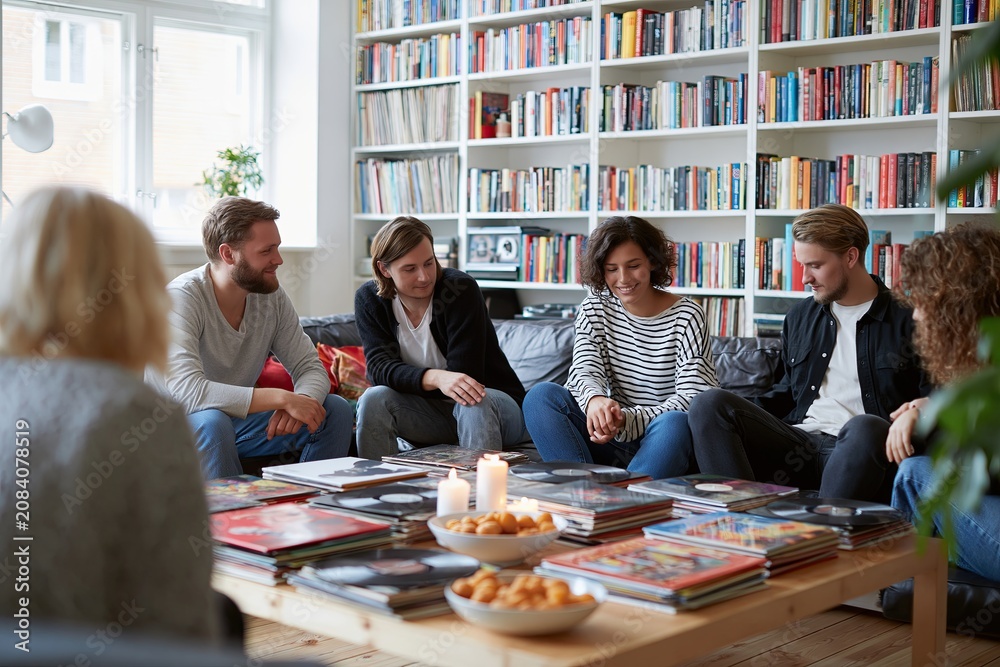 Fototapeta premium Group of friends sitting around coffee table with vinyl records social gathering
