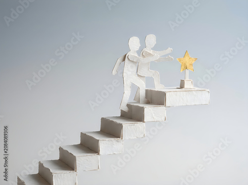 Two paper figures climbing stairs to a star