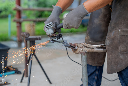 Photos Professional farrier using angle grinder on horseshoe with bright sparks flying,