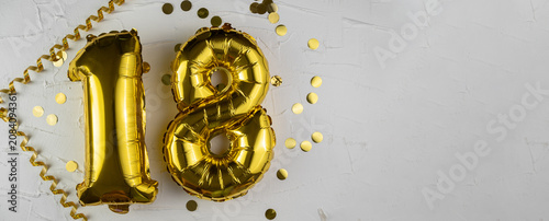 Yellow Gold foil balloon number eighteen on a concrete background. Birthday card with lettering 18. Anniversary concept. For anniversary, birthday, wedding event, new year celebration.