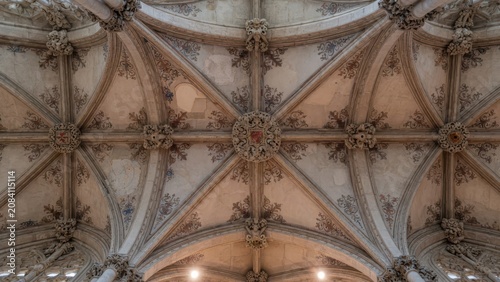 Intricate stone vaulting displays ornate carved bosses and hand painted floral flourishes within a historic portuguese cathedral showcasing majestic manueline stonework patterns across the grand