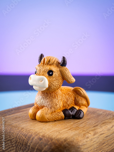 Close-up of a cute miniature cow figurine in an interior setup on a purple background