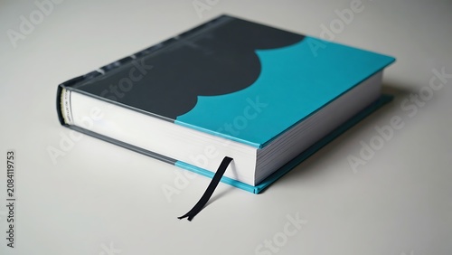 A hardcover book with a blue and gray cover, resting on a white surface with a black bookmark.