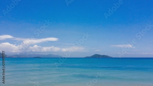 Serene seascape featuring a tranquil turquoise sea under a clear blue sky with distant islands.