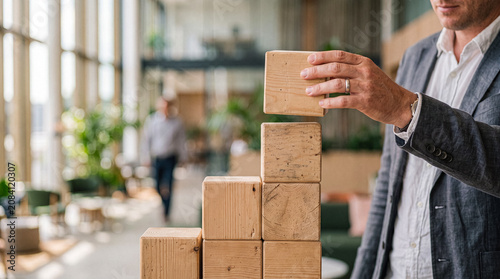 Foto Male hand precisely stacking natural wooden blocks, symbolizing business growth and strategic development in a bright