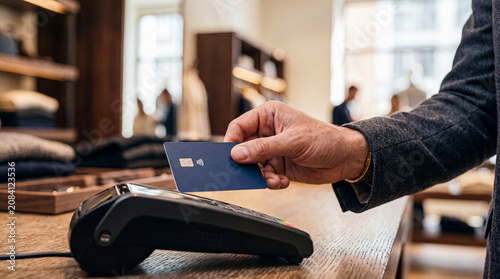 Foto Close-up of a customer making a contactless payment with a blue credit card at a point of sale terminal
