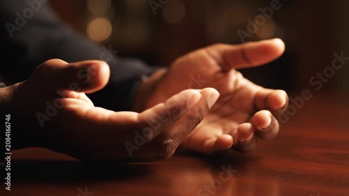 Hands resting peacefully on a polished wooden desk.