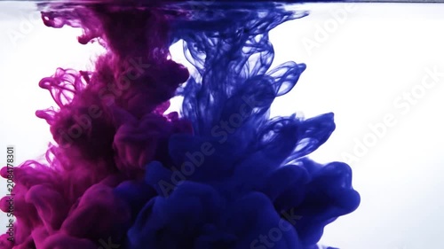 Intense blue ink plume expanding in water on white.
