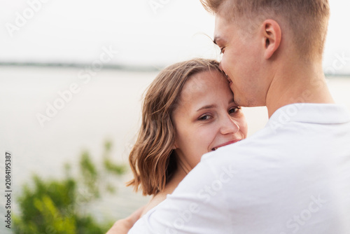Quadro su tela Young couple sharing a tender moment with a forehead kiss by the water