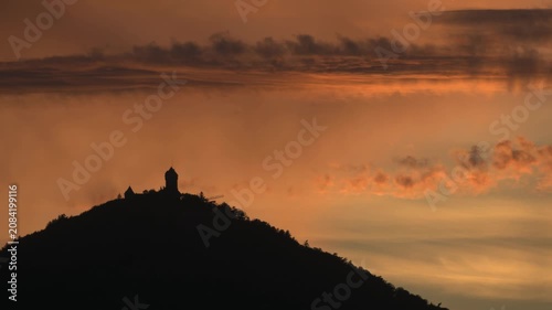 Silhouette of Haut Koenigsbourg castle at sunset. Orange clouds scroll by in timelapse.