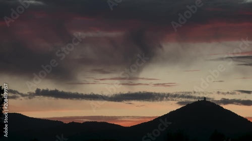 Silhouette of Haut Koenigsbourg castle at sunset. Orange clouds scroll by in timelapse.