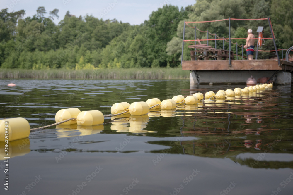 Obraz premium Buoys marking the area of ​​a supervised swimming zone. A lakeside swimming area in summer. 