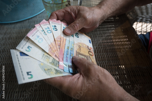 Fotografie An elderly man holds euro banknotes in his hands.