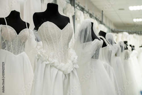Fotografie Elegant white wedding dresses on mannequins in bridal boutique display