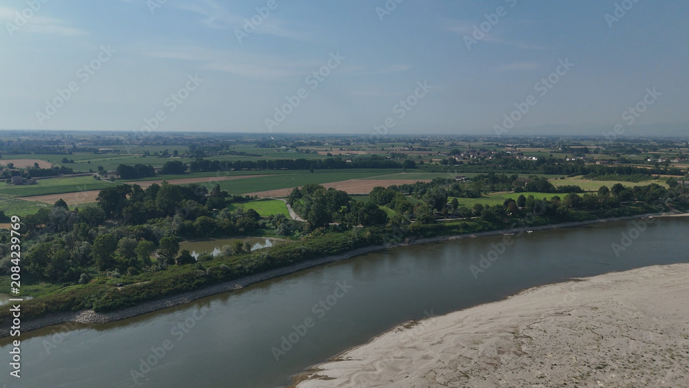 Fototapeta premium Po River's dramatic low water level showcasing extensive dry riverbed and exposed sand bars, illustrating the severe drought and ongoing water crisis impacting the Italian landscape and agriculture