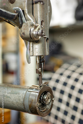 Foto Industrial sewing machine needle and presser foot stitching patterned fabric in