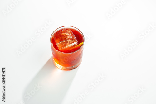 Orange Cocktail with Ice Cube and Citrus Peel in Rocks Glass on White Background with Copy Space